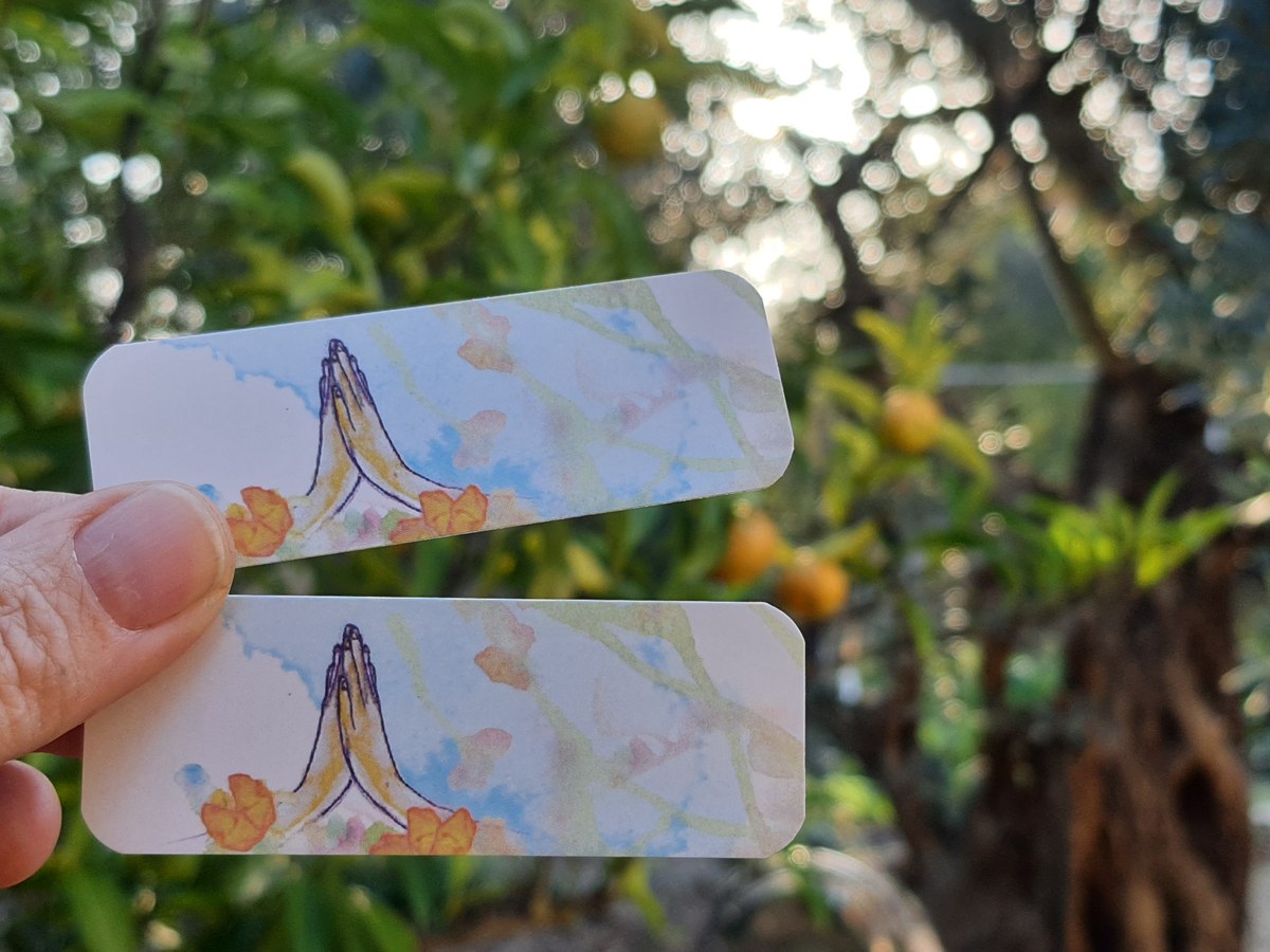 יד מחזיקה שני קלפי הודיות הפוכים, ברקע עץ הדרים